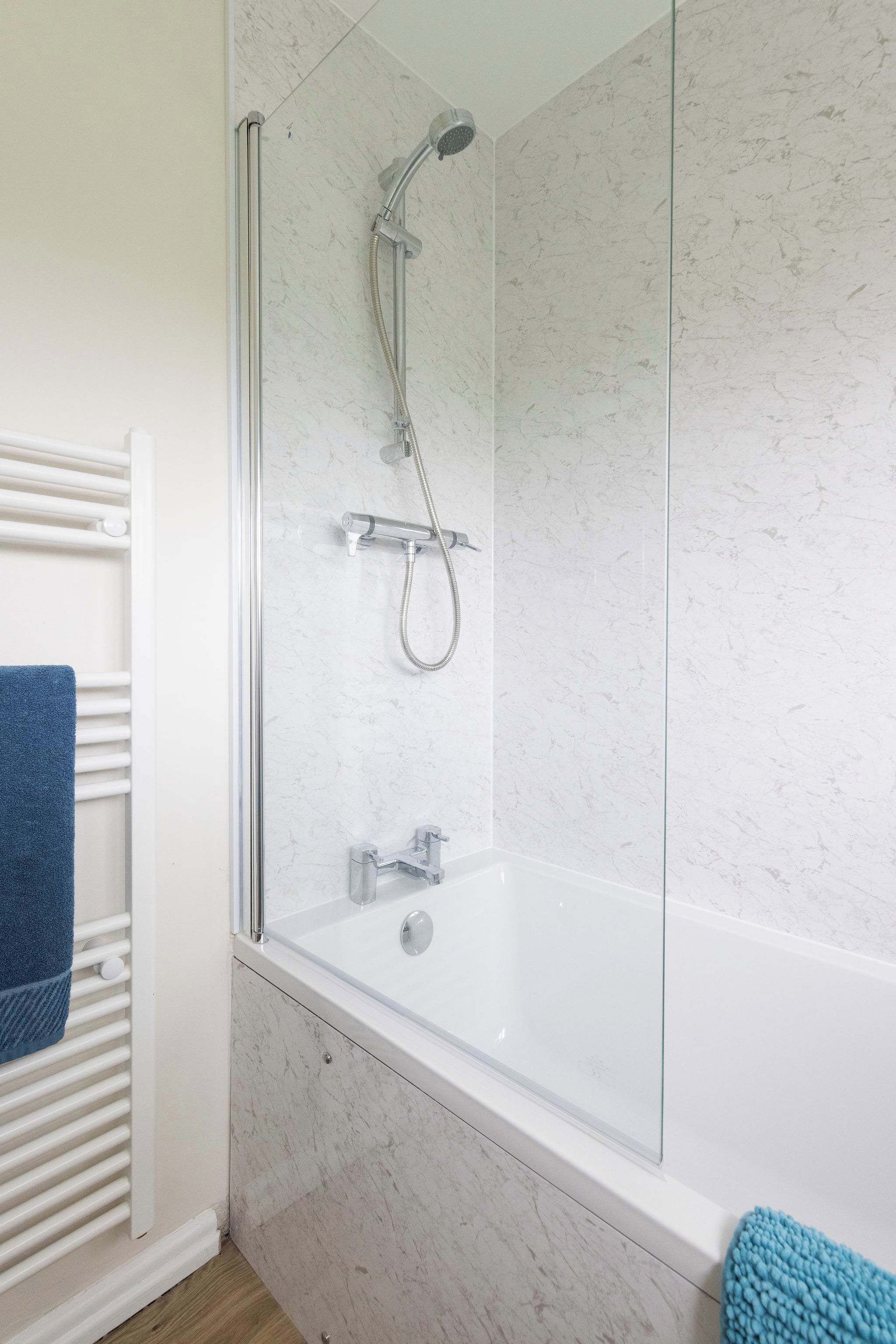 Un bagno moderno con doccia vetrata, una vasca da bagno bianca e un termosifone bianco.