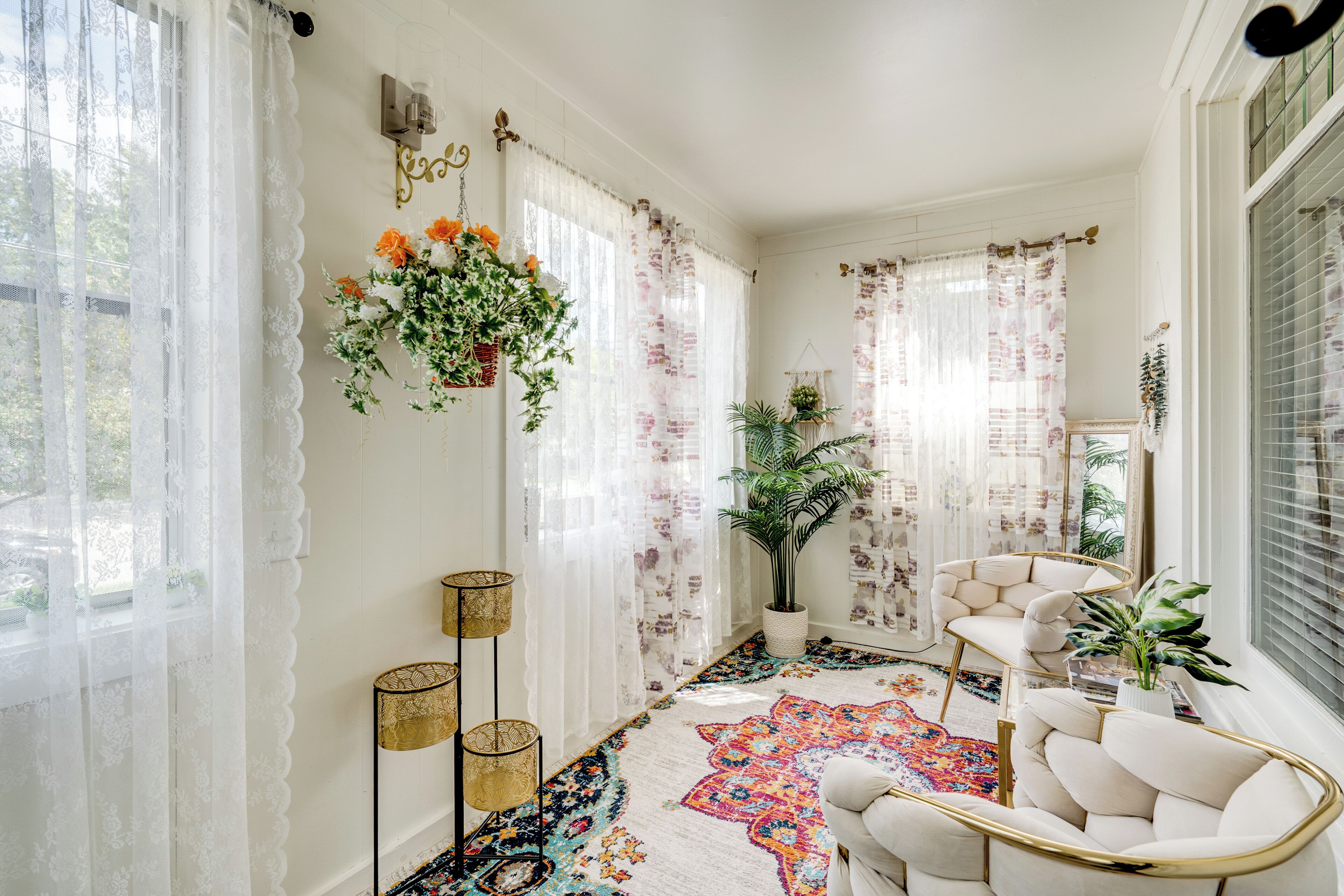 Een gezellige kamer met een kamerbreed tapijt, een hangplant en een witte fauteuil.