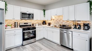 A modern kitchen with white cabinets, stainless steel appliances, and a brick backsplash. - 1 Mi to Dtwn Elgin: Dutch Colonial w/ Lovely Patio (Elgin)