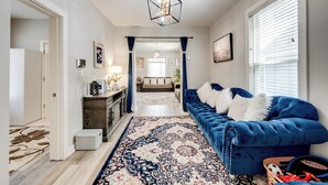 A hallway with a blue sofa, a patterned rug, and a ceiling light fixture. - 1 Mi to Dtwn Elgin: Dutch Colonial w/ Lovely Patio (Elgin)