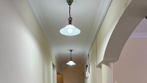 Een gang met witte wanden, een betegelde vloer en twee hanglampen.