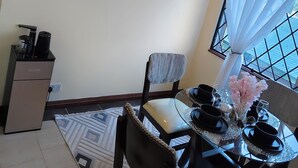 Een eetgedeelte met een ronde tafel, stoelen en een koffieapparaat.