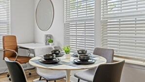 A dining area with a round table set for four, surrounded by chairs, and a window with blinds. - 3BR Townhouse Mins to Uptown Charlotte (Charlotte)