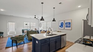 A modern kitchen with dark cabinets, a central island with a sink, and pendant lighting. - 3BR Townhouse Mins to Uptown Charlotte (Charlotte)