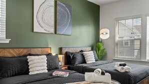 A hotel room with two beds, dark bedding, a green accent wall, and a large window with blinds. - 3BR Townhouse Mins to Uptown Charlotte (Charlotte)