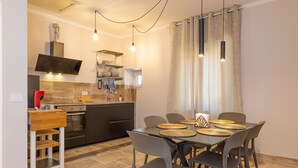 A compact kitchen with modern appliances, a dining area with a table set for four, and a large window with curtains. - Villa in Volterra with 2 bedrooms sleeps 6 (Volterra)