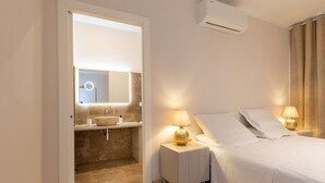 A hotel room with a bed, bedside lamps, a bathroom with a sink and mirror, and an air conditioning unit. - Villa in Volterra with 2 bedrooms sleeps 6 (Volterra)