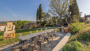 An outdoor patio with a table and chairs, a barbecue grill, and a stone building with a flag. - Villa in Volterra with 2 bedrooms sleeps 6 (Volterra)
