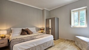 A bedroom with a bed, bedside lamps, a wardrobe, a window, and a woven bench. - Villa in Volterra with 2 bedrooms sleeps 6 (Volterra)