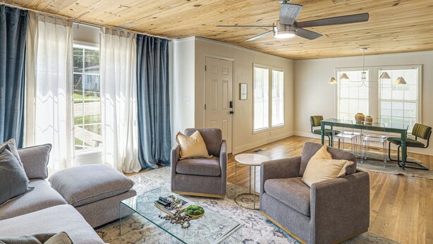 A spacious living room with a wooden ceiling, a glass coffee table, and a dining area with a table and chairs. - From the Square to Ole Miss: Historic Oxford Home (Oxford)
