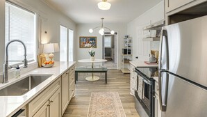 A modern kitchen with stainless steel appliances, a central island, and a dining area. - From the Square to Ole Miss: Historic Oxford Home (Oxford)