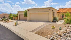 A residential property with a beige garage, a landscaped front yard with rocks and cacti, and a clear blue sky. - Quiet Townhome w/ Mountain Views in Green Valley (Green Valley)