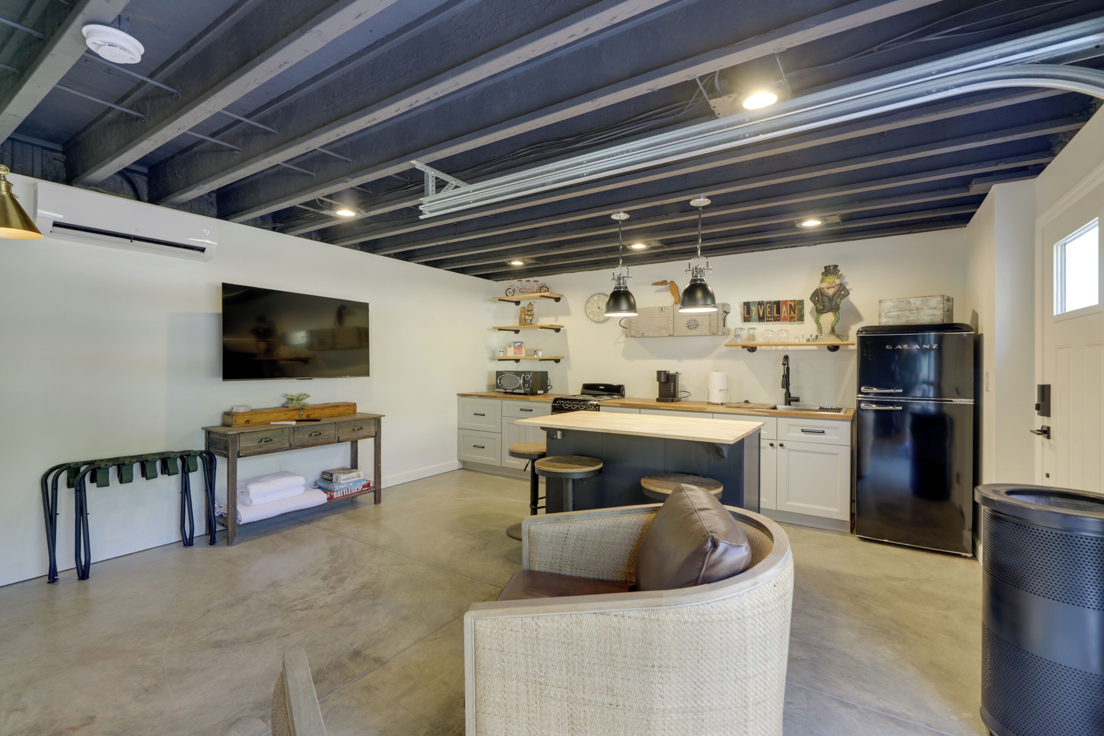 A modern kitchen with a bar area, white cabinetry, and a black refrigerator.