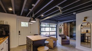 A modern kitchen with a central island, bar stools, and a seating area with a sofa and chairs. - Unique Studio on Obanyon Creek in Dtwn Loveland! (Loveland)