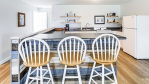 A modern kitchen with a central island, white bar stools, wooden flooring, and built-in appliances. - Private Boat Ramp see explanation below (Aurora)