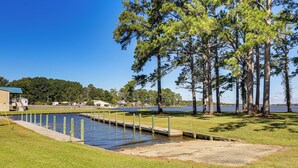A waterfront property with a dock, grassy areas, and a backdrop of trees and a body of water. - Private Boat Ramp see explanation below (Aurora)