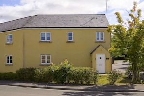 A yellow two-story building with a flat roof, multiple windows, and a small door.
