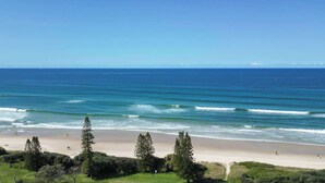 A beach with waves, trees, and a clear sky.
