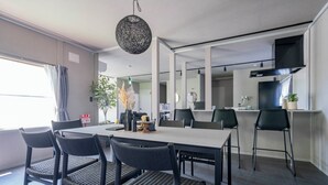 A modern dining area with a large table, black chairs, and a hanging light fixture. - GROUNDBLOOM YIG STAY (Furano)