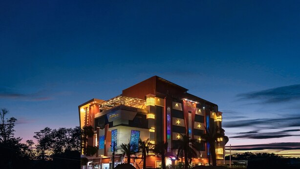 A multi-story hotel with a modern design, featuring a prominent entrance and illuminated signage.