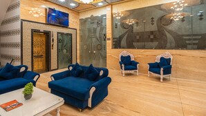 A lobby with blue sofas, a white table, and a large mirror.