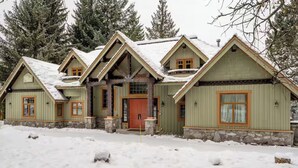 En hytte med stensokkel, flere tagkviste og en midterliggende inngang.