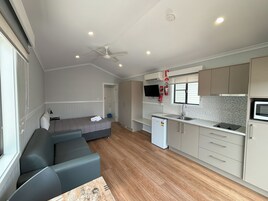 Un espacio habitable compacto con kitchenette, sofá y ventilador de techo.