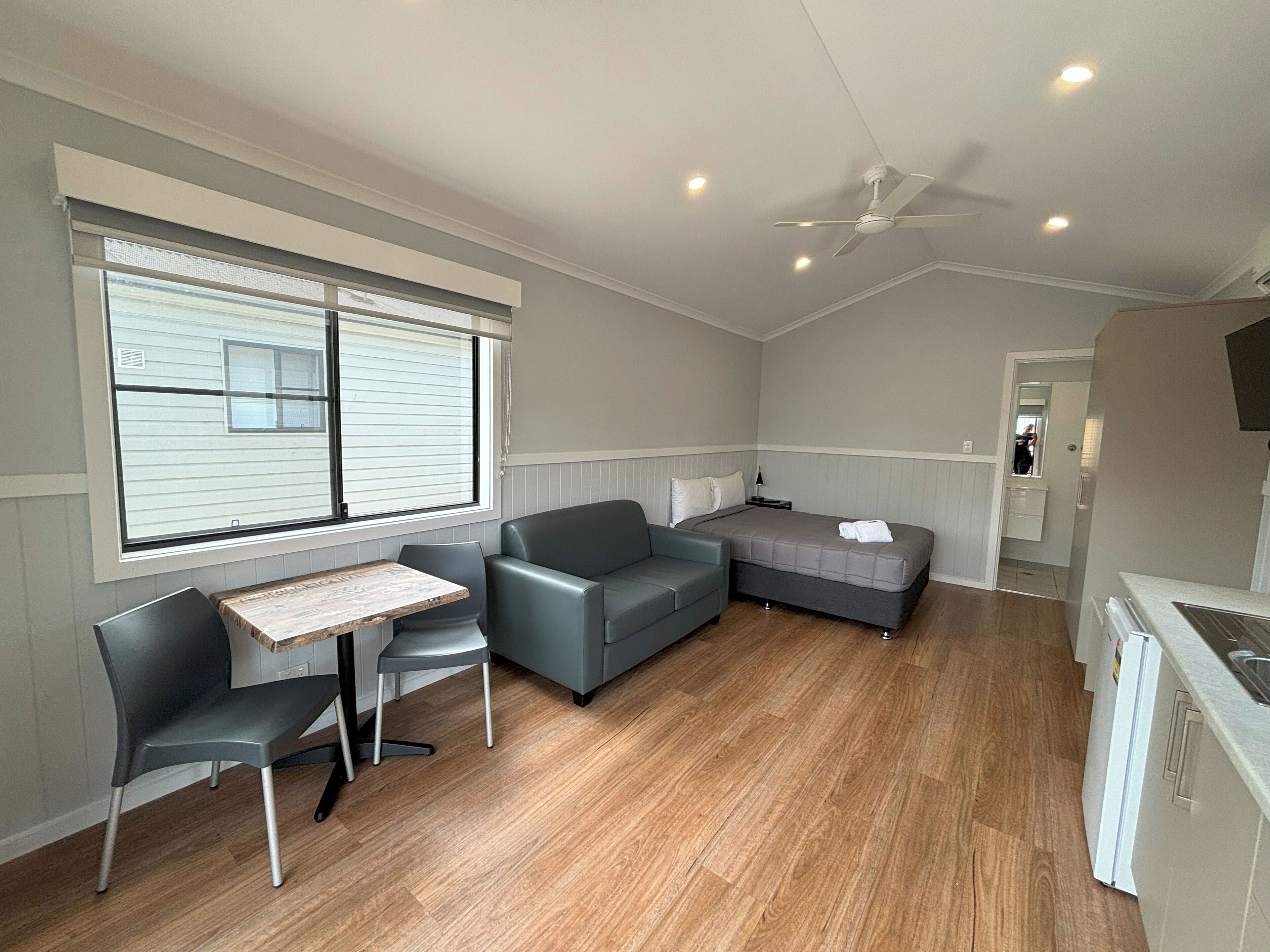 A compact, well-lit room with a dining area, a sofa, and a bed.