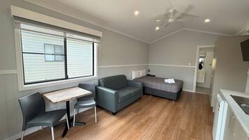 A compact, well-lit room with a dining area, a sofa, and a bed.