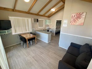 A compact living space with a kitchen, dining area, and a living room with a sofa. - Heatherbrae Holiday Village (Heatherbrae)