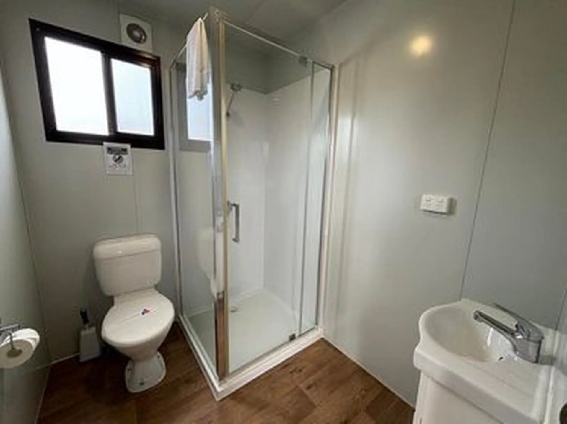 Une salle de bain comprenant des toilettes, une douche à parois de verre et un lavabo.
