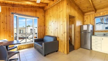 Un intérieur en bois comprenant un coin repas, un canapé, un réfrigérateur et un plan de travail de cuisine.