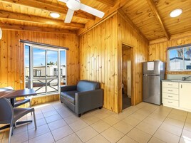 Un interior de madera con comedor, sofá, refrigerador y mostrador de cocina.