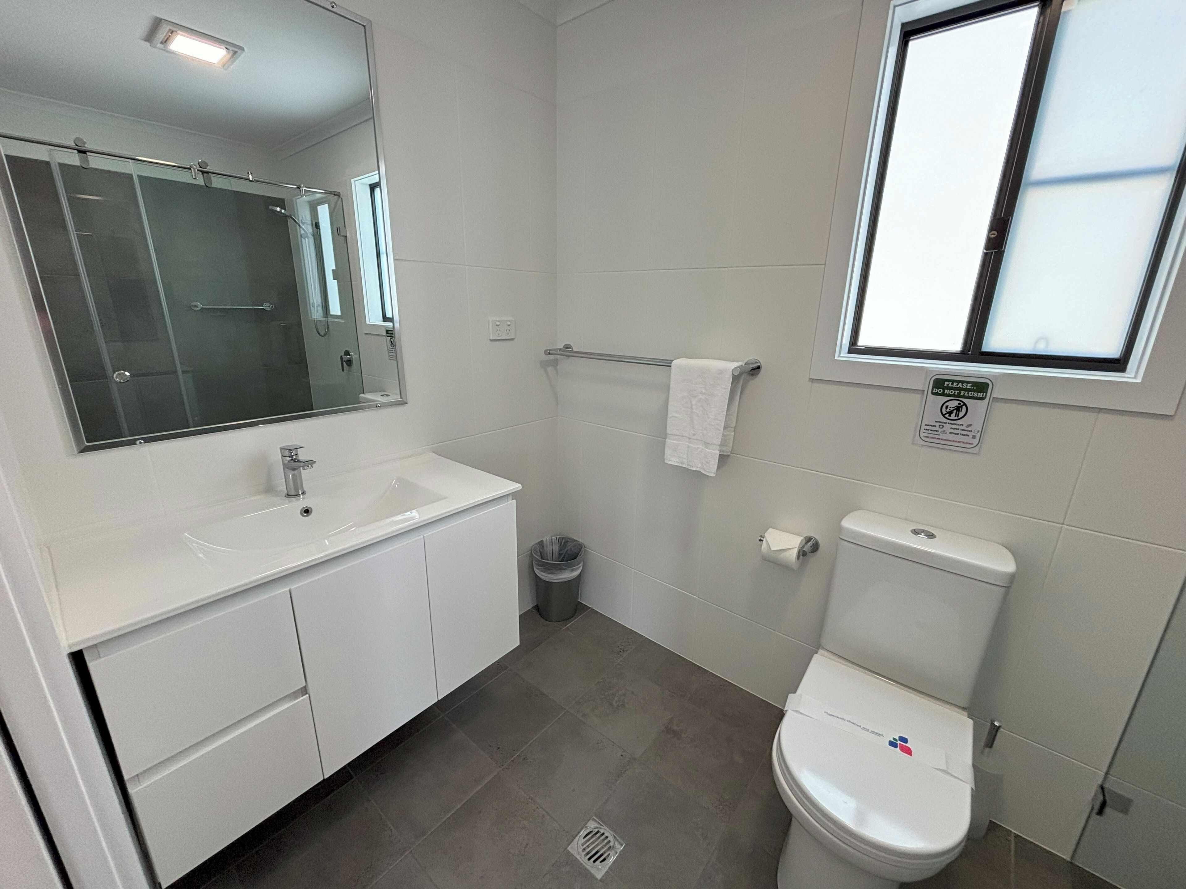 Een moderne badkamer met een wit wastafel, spiegel en toilet.