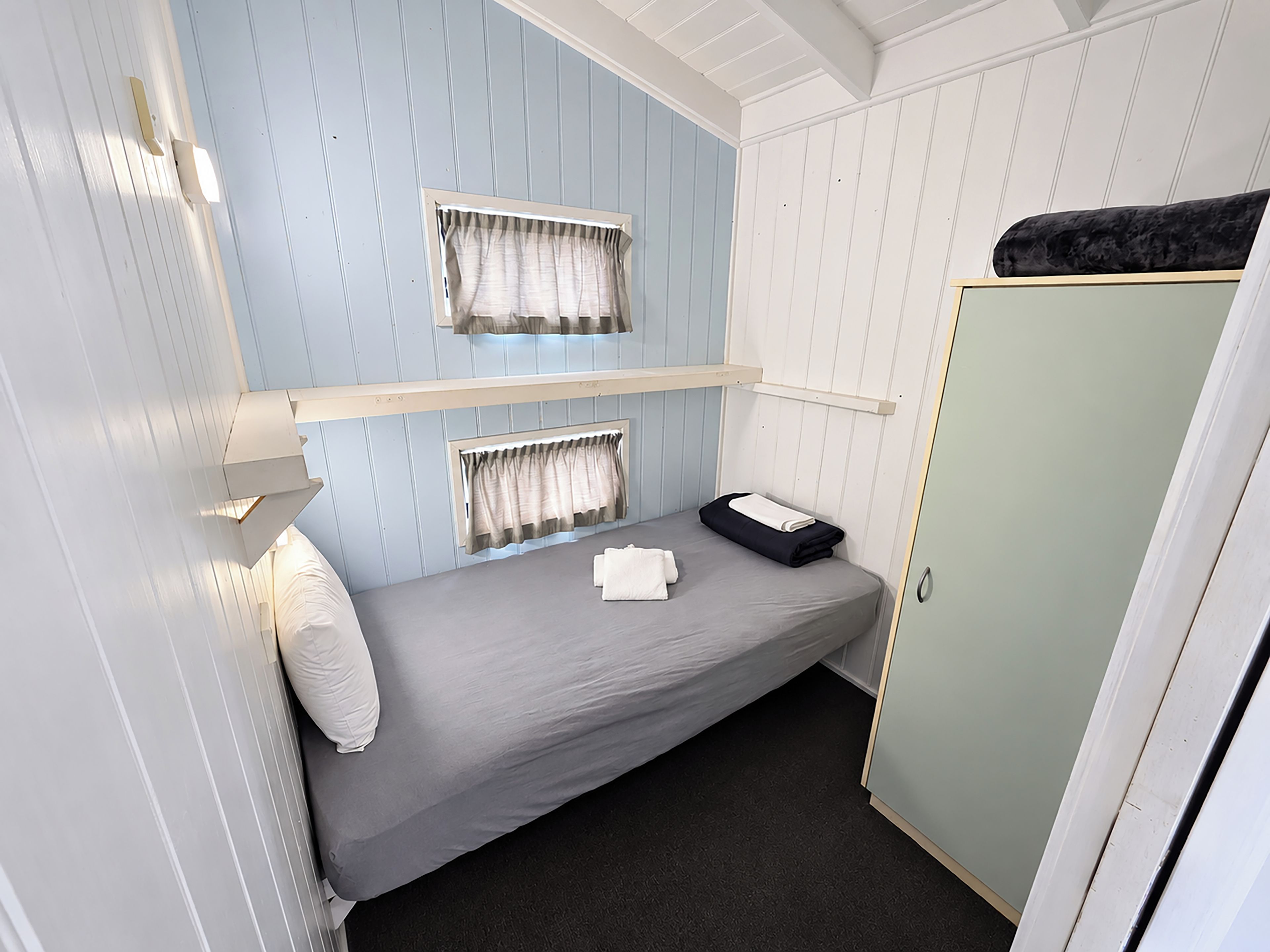A compact room with bunk beds, a wardrobe, and a small table with a folded towel.