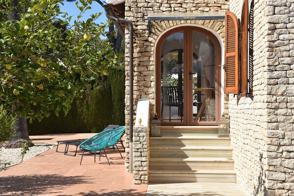 A stone building with a wooden door and steps leading to a balcony.