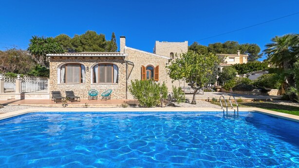 Un bâtiment en pierre doté d’une piscine, de deux chaises longues et d’un petit jardin.