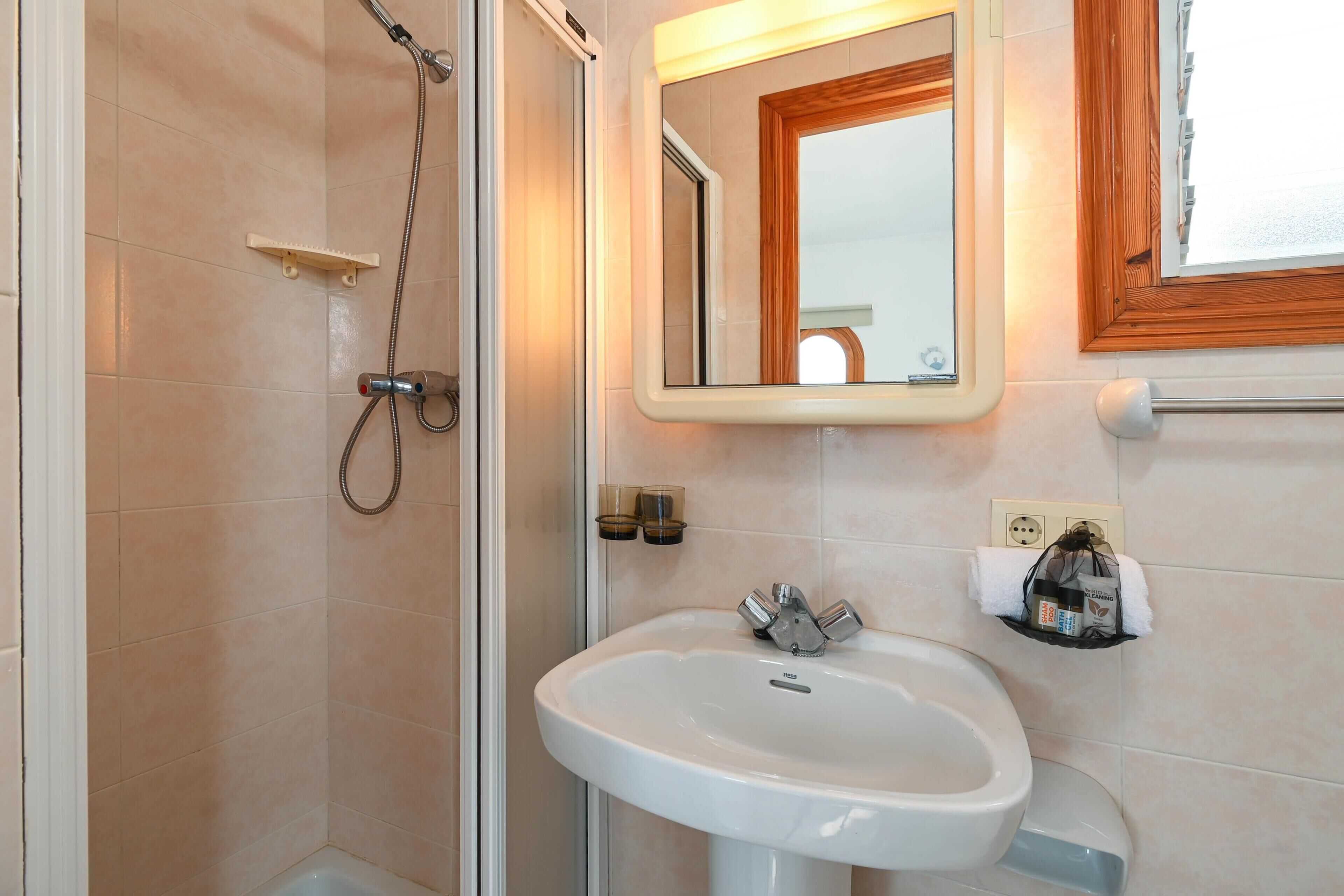 Une salle de bain avec une douche, un lavabo et un miroir.