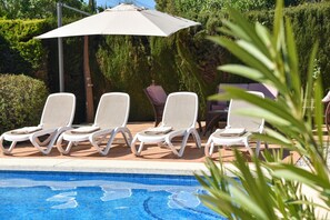 Un espace aménagé au bord de la piscine, avec des chaises longues et un parasol.