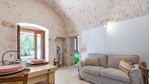 A cozy living room with a sofa and a dining area with a table set for two. - Lamia Terra 3br, Terrace & BBQ (Castellana Grotte)