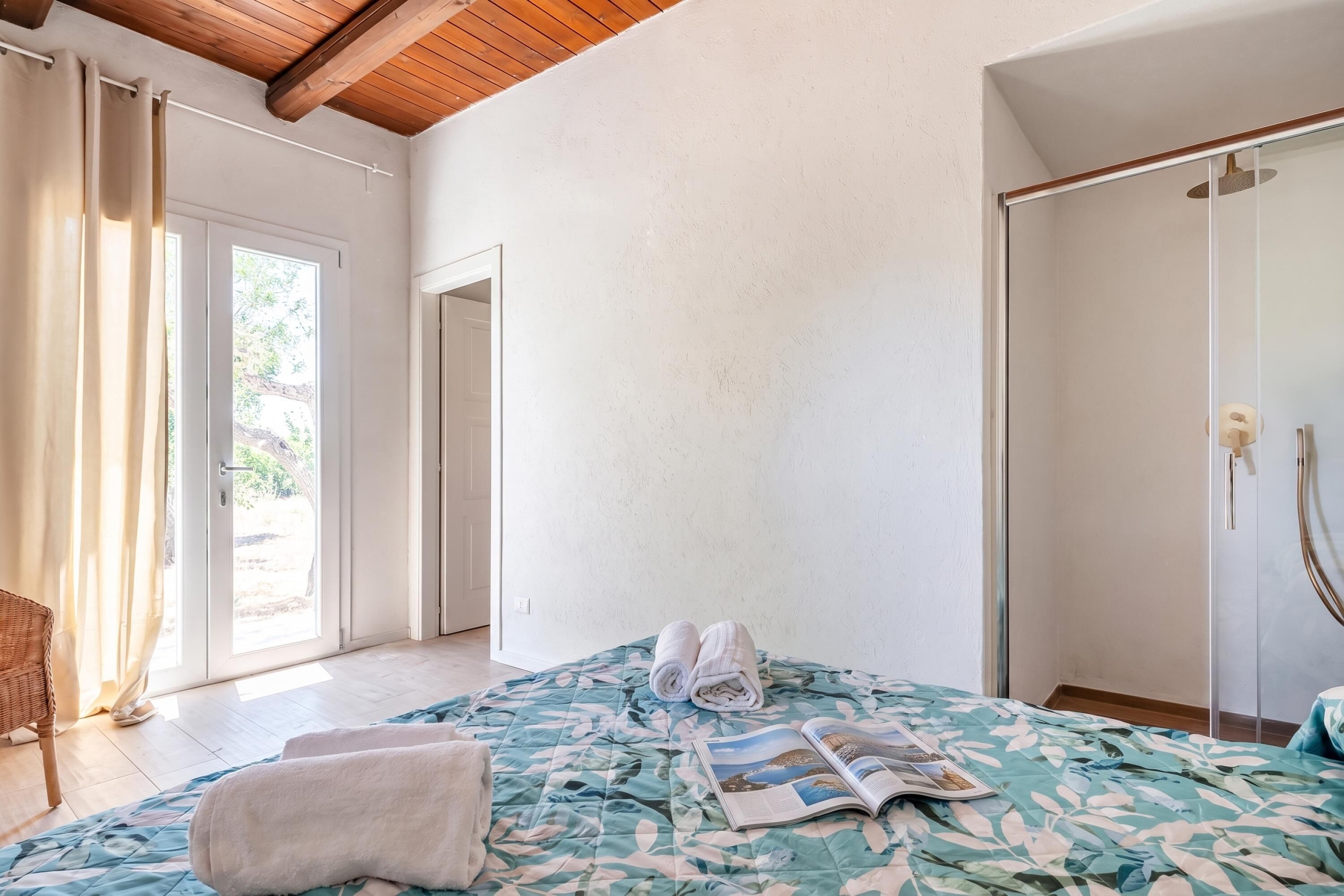 Une chambre à coucher comprenant un lit, une porte, une fenêtre et un espace douche.