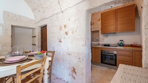 A rustic kitchen with a wooden table and chairs, a sink, and a stove. - Lamia Terra 3br, Terrace & BBQ (Castellana Grotte)