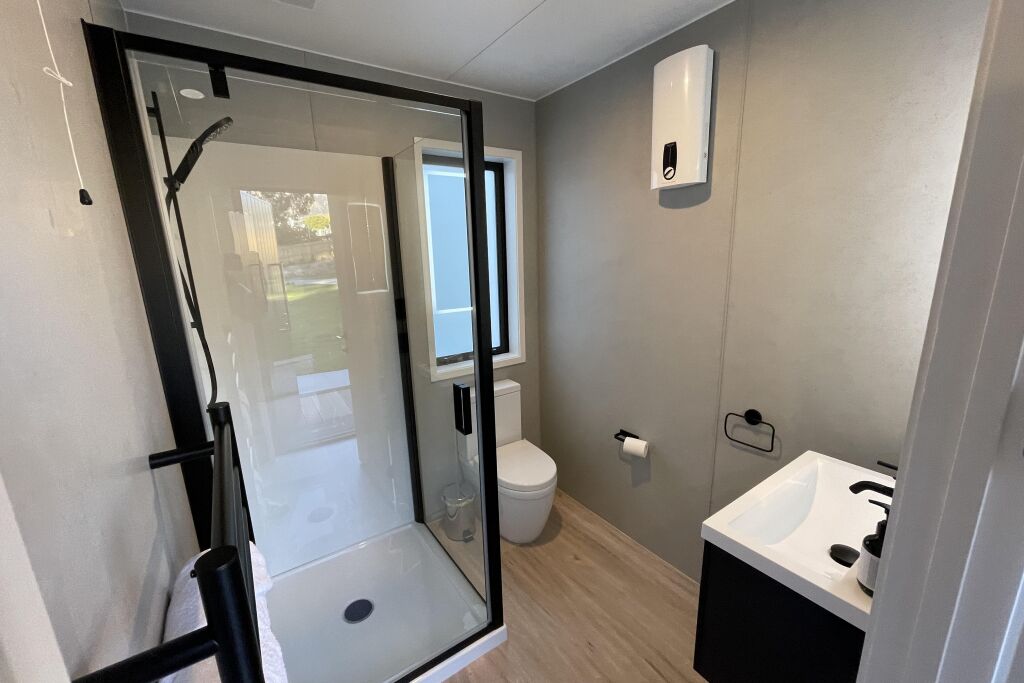 Une salle de bain moderne avec une douche à l’italienne, des toilettes et un lavabo.