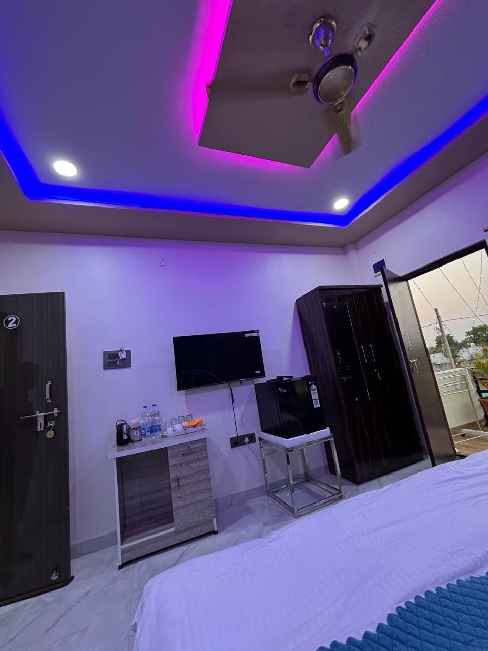 Een moderne slaapkamer met een bed, een televisie, een kledingkast en een klein bureau met stoel.