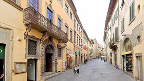 Una calle estrecha bordeada de edificios con balcones y comercios.