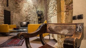 Un accogliente soggiorno con parete in pietra, un divano giallo e una sedia in legno.