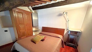 Una camera da letto con un letto, un'armadietto in legno, un comodino, una lampada e un tavolino.
