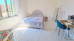 A bedroom with a bed, bedside tables, a desk, and a chair.