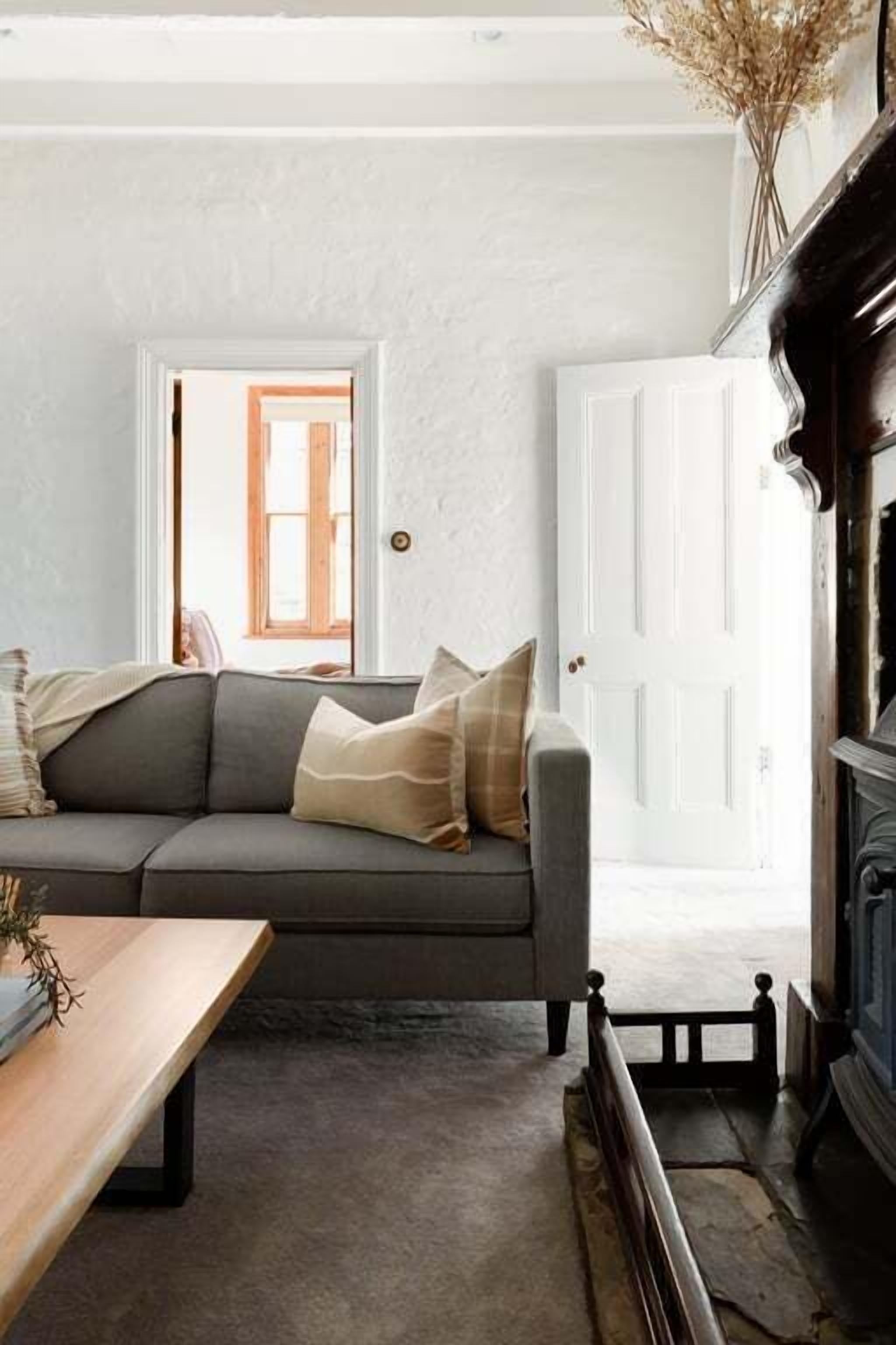 A cozy living room with a grey sofa, a wooden coffee table, and a fireplace.
