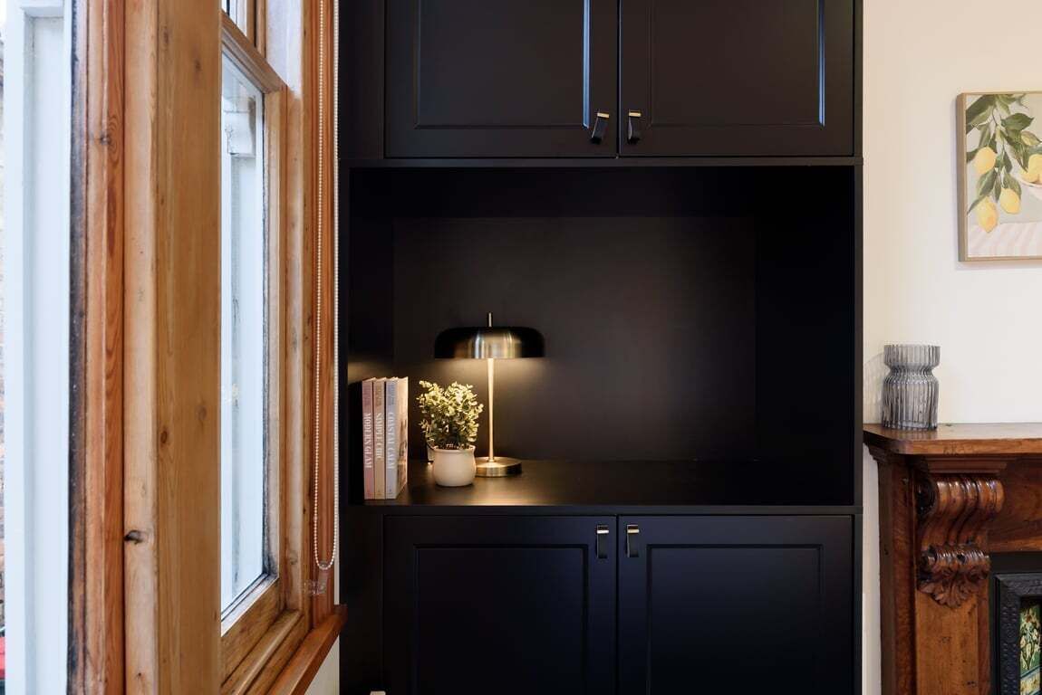 A dark wooden cabinet with a small table and a lamp.